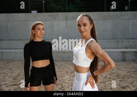 Stehen und posieren. Zwei sportliche Frauen sind zusammen draußen. Stockfoto