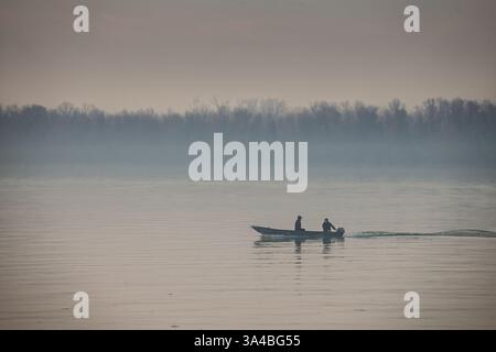 BELGRAD, SERBIEN - 12. OKTOBER 2024: Zwei Fischer in einem Schnellboot in der Abenddämmerung auf der Donau in Belgrad, Serbien Stockfoto