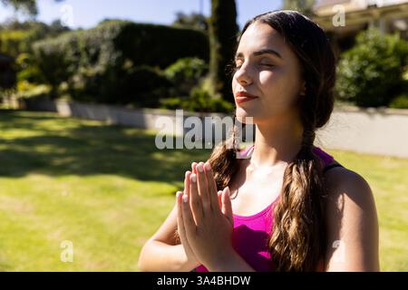 Junge Frau, die im Freien meditiert, friedliche Momente im sonnigen Garten genießt, Kopierraum Stockfoto