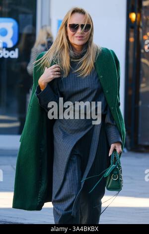 Amanda Holden verlässt die Global Studios, nachdem sie ihre Heart Radio Frühstücksshow in einem grauen Hosenanzug, grünem Mantel und Riemensandalen präsentiert hat. Stockfoto