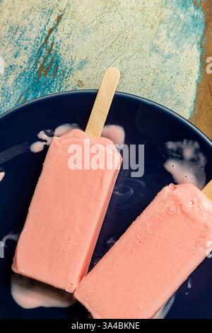 Eis aus schwarzen Beeren, die auf blauem Schälchen und farbenfrohem Hintergrund schmelzen. Leerzeichen Stockfoto