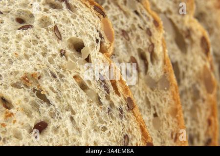 Scheiben frisch gebackenes Mehrkornbrot mit sichtbaren Samen und Nüssen, die eine gesunde und nahrhafte Speisenauswahl betonen, ideal für ein gesundes und natürliches Stockfoto