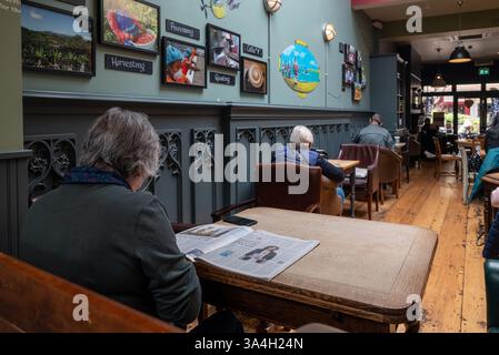 Ältere Menschen saßen in einem Café, tranken und lasen allein. März 2025. Stockfoto