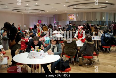 Besucher, die im Bereich der Cup Noodles Factory im Cup Noodles Museum in Yokohama, Japan, maßgeschneiderte Behälter mit Nissin Cup Nudeln herstellen. Stockfoto