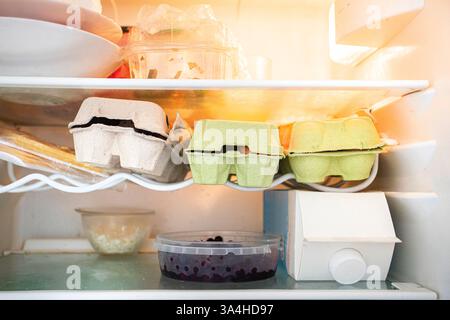 Offener Kühlschrank mit Eiern, Milchprodukten, einer Flasche Wein und Gemüse. Was man kochen kann Stockfoto