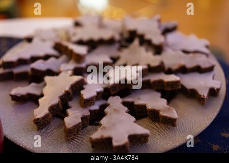Ein köstlicher Teller mit baumförmigen Weihnachtsplätzchen, garniert mit weißer Glasur, ordentlich auf einer festlichen Platte angeordnet. Stockfoto