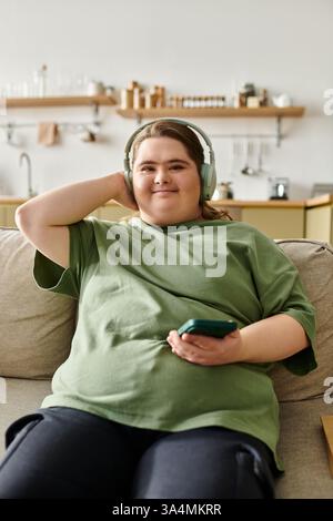 Eine junge Frau mit Down-Syndrom entspannt sich auf einem Sofa und hört ihre Lieblingslieder bequem. Stockfoto