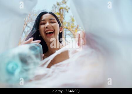 Freudiges Recycling. Junge Frau, die mit Freude Recyclingmaterialien aus einer einzigartigen Perspektive entdeckt und dabei die Natur genießt. Stockfoto