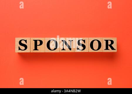 Word Sponsor aus Holzwürfeln mit Buchstaben auf dunkelorangefarbenem Hintergrund, Draufsicht Stockfoto