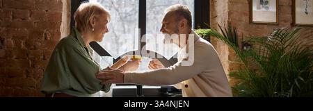 Ein Paar mittleren Alters teilt einen freudigen Moment mit Getränken in einem charmanten Café, strahlt Wärme aus, Banner Stockfoto