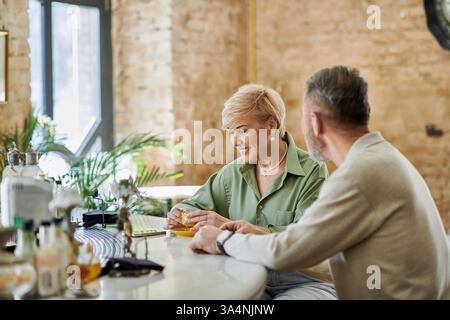 Ein fröhliches Paar lacht, während es an einer stilvollen Bar einen Drink schlürft und ihr Date genießt. Stockfoto