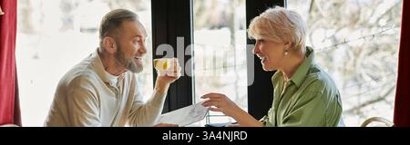 Ein Paar lacht über Drinks in einem Café, macht schöne Erinnerungen zusammen, Banner Stockfoto