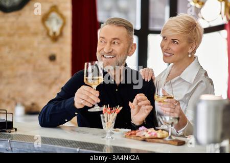 Ein Paar mittleren Alters teilt einen freudigen Moment bei einem Drink in einem warmen, einladenden Café. Stockfoto