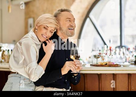 Ein Paar mittleren Alters teilt sich in einer gemütlichen Bar mit Lachen und Wärme und genießt zusammen erlesene Getränke. Stockfoto