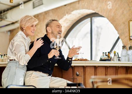 Ein Paar mittleren Alters teilt sich einen freudigen Moment bei einem Drink in einem gemütlichen Restaurant, das Romantik genießt. Stockfoto