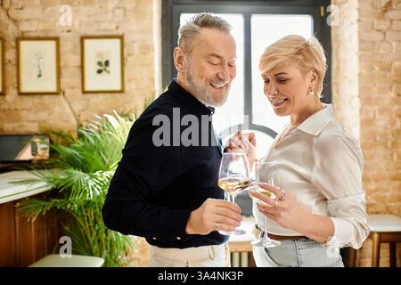 Ein Paar mittleren Alters lacht und trinkt und genießt sich in einer warmen Atmosphäre. Stockfoto