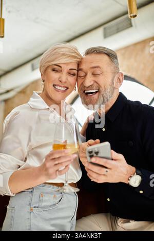 Ein Paar mittleren Alters lacht und trinkt bei einem schönen Abend in einer gemütlichen Bar. Stockfoto