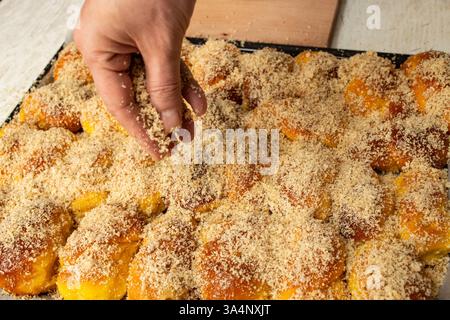Handbestreute geriebene Nüsse auf sfintisori. Rumänische Küche. Hausgemachte Mucenici, traditionelle Desserts in der Abbildung 8, mit Honig bestrichen Stockfoto