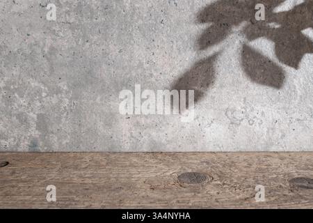 Wunderschöne Kulisse mit texturierten Wänden aus Zement, Schreibtisch aus verwittertem Holz und Schatten der Bäume, Kopierraum Stockfoto
