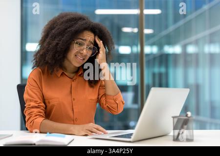 Verärgert frustrierte Frau, die im Büro mit einem Laptop arbeitet. Geschäftsfrau ist unzufrieden mit dem Lesen der Online-E-Mail-Benachrichtigung vom Laptop. Stockfoto
