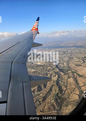 Ein atemberaubender Blick aus der Luft von einem Flugzeugfenster aus, der weite Himmel, Wolken und Landschaften unter sich zeigt und die Schönheit der Reise von oben erfasst. Stockfoto