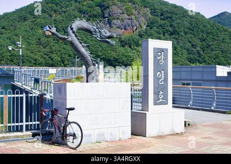 Damyang County, Südkorea - 23. September 2020: Ein Rennrad lehnt sich an die Basis einer Drachenstatue am Damyang See, mit der malerischen Kulisse von t Stockfoto