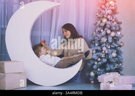 Glückliche Mutter mit Sohn im Wohnzimmer in der Nähe von dekoriertem Tannenbaum Stockfoto