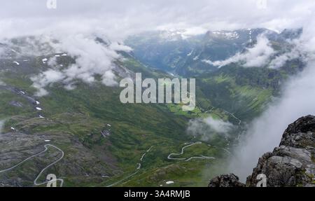 Atemberaubende Aussicht aus der Vogelperspektive von Dalsnibba in Norwegen mit gewundenen Bergstraßen, üppigen grünen Tälern und teilweise verdeckten Nebelwolken Stockfoto