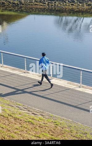 Männer, die an sonnigen Tagen in blauer Jacke den Fluss entlang laufen. Hochwertige Fotos Stockfoto