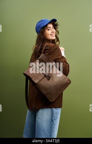 Eine junge Frau lächelt selbstbewusst in trendigen Kleidern, ihre stilvolle braune Tasche über der Schulter. Stockfoto