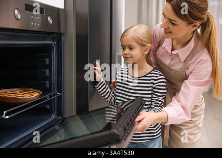 Mutter und Tochter backen Kuchen im Ofen drinnen Stockfoto