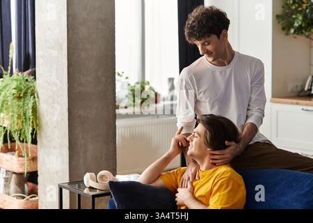 Ein nettes schwules Paar teilt einen zärtlichen Moment, während es sich in seinem stilvollen Apartment entspannt und die Liebe feiert. Stockfoto