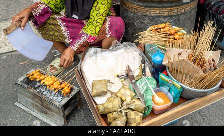 Eine indonesische Frau, die Hühnersatay und Ketupat in yogyakarta zubereitete Stockfoto