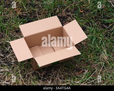 Ein leerer Karton, der draußen auf Gras liegt. Nahaufnahme. Stockfoto