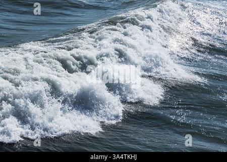 Ein fesselndes Bild von Meereswellen, die mit weißem Schaum brechen, Sonnenlicht reflektieren und ein Gefühl von Energie und Schönheit der Natur hervorrufen Stockfoto