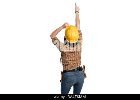 Eine Bauarbeiterin von hinten gesehen, mit gelbem Schutzhelm und Werkzeuggürtel, nach oben gerichtet. Ideal für Konzepte wie Führung, dir Stockfoto