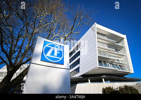 Friedrichshafen, Deutschland. März 2025. Das ZF Friedrichshafen Forum wird von der Abendsonne beleuchtet, im Vordergrund steht eine Stele mit dem ZF Friedrichshafen Logo. Quelle: Felix Kästle/dpa/Alamy Live News Stockfoto