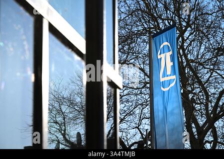 Friedrichshafen, Deutschland. März 2025. Das ZF Friedrichshafen Forum wird von der Abendsonne beleuchtet, davor fliegt eine Fahne mit dem ZF Friedrichshafen Logo. Quelle: Felix Kästle/dpa/Alamy Live News Stockfoto