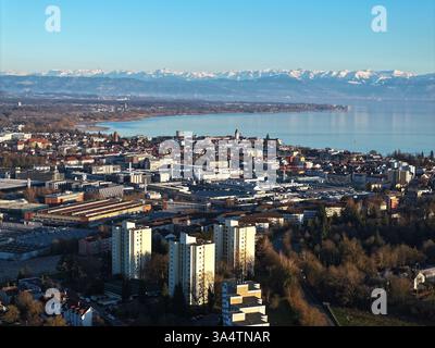 Friedrichshafen, Deutschland. März 2025. Die Stadt Friedrichshafen liegt am Bodensee, während im Hintergrund die Alpen in der Schweiz und Österreich zu sehen sind. (Luftaufnahme mit einer Drohne) Credit: Felix Kästle/dpa/Alamy Live News Stockfoto