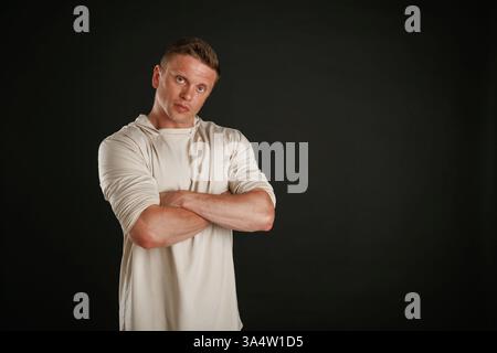 Posieren, Arme gekreuzt. Der Mann ist vor Hintergrund im Studio. Stockfoto