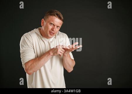 Sehen Sie sich dies an, Kopierraum, zeigt auf der Handfläche. Der Mann ist vor Hintergrund im Studio. Stockfoto