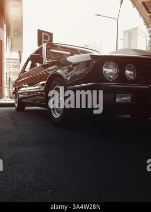Vorderansicht rechts eines alten braunen BMW der 1980er Jahre. Oldtimer parkt auf dem Parkplatz – Nahaufnahme von Scheinwerfer, Kotflügel, Stoßfängerhaube und Rad. Stockfoto