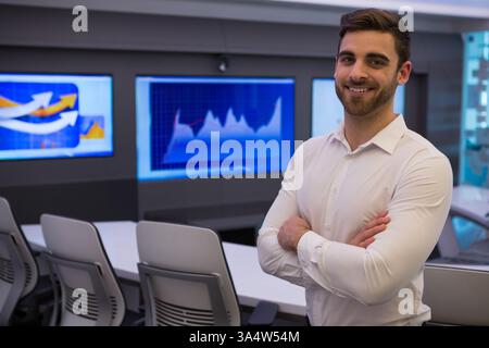 Selbstbewusster Geschäftsmann im modernen Büro, stehend mit überkreuzten Armen, lächelnd in die Kamera, Kopierraum Stockfoto