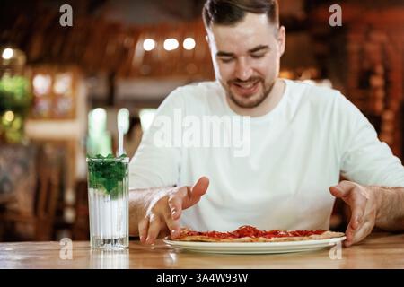 Der Mann sitzt im Restaurant und isst eine Pizza. Stockfoto