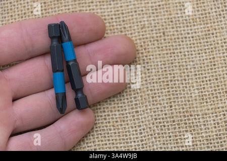 Schwarz-blauer Aufprallmesser in der Hand auf einem Sackleinen-Hintergrund, Nahaufnahme. Stockfoto