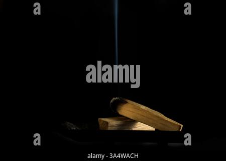 Bursera graveolens Palo Santo ein brennendes heiliges Holz mit Rauch auf schwarzem Hintergrund intensives Aroma Harmonie Frieden und Ruhe Reinigung medit Stockfoto