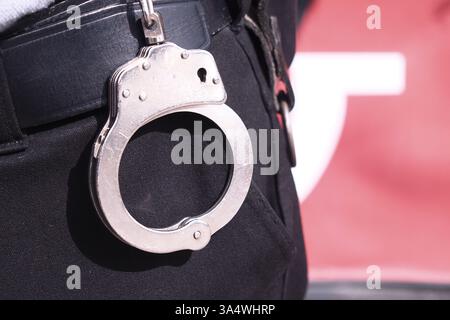 Polizist trägt Handschellen während einer Strafverfolgungsmaßnahme Stockfoto
