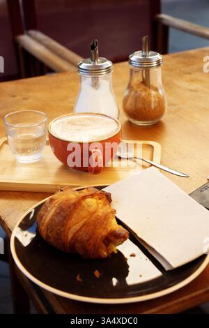 Typisches Frühstück auf Menorca mit einer Tasse Kaffee, Croissant und einem Glas Wasser Stockfoto