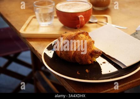 Typisches Frühstück auf Menorca mit einer Tasse Kaffee, Croissant und einem Glas Wasser Stockfoto