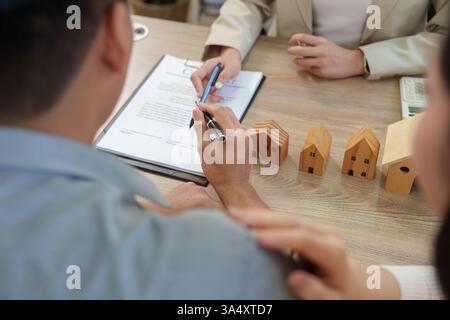 Immobilienberatung. Ein Agent erklärt einem Paar die Vertragsdetails vor dem Kauf eines Hauses. Stockfoto
